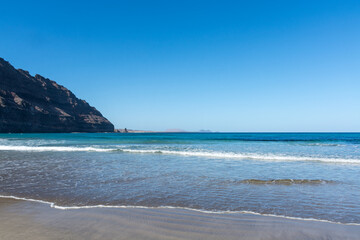 Black lava rocks and water waves of Atlantic ocean, nature landscape on Lanzarote, Canary islands, Spain