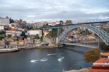 Fototapeta na wymiar Porto, Portugal, October 31,2020. View on bridge, colorful old houses on hill in old part of city and embankment of Douro river in rainy day