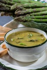 Bowl with creme soup made from fresh green asparagus vegetables close up