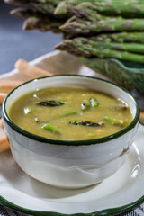 Bowl with creme soup made from fresh green asparagus vegetables close up