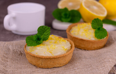 Tartlets with lemon cream and mint on a gray background.