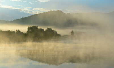 Misty lake in the hills at summer dawn. Arló, Hungary.