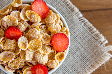 Cornflakes with milk and pieces of strawberry, healthy breakfast.