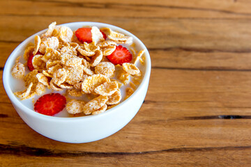 Cornflakes with milk and pieces of strawberry, healthy breakfast.