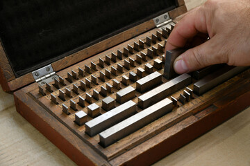 The worker selects the gauge blocks to measure.