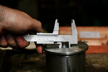 The worker measures the inner diameter of the hole on the adapter sleeve with a vernier caliper.