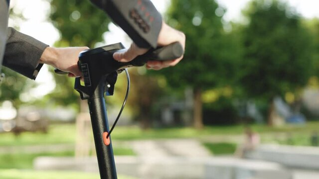 Energy efficient travel vehicle concept of 4k resolution. Close up of unrecognizable business man riding electric scooter in the city. Modern eco friendly transport. Ecology and urban lifestyle
