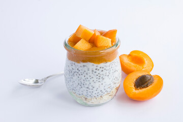 Pudding with chia seed, oat flakes and apricot in the glass jar on the white background. Close-up.