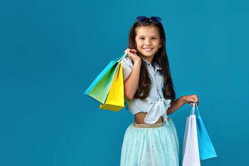 happy little caucasian child girl holds many shopping bags