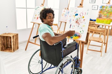 Young african american disabled artist man sitting on wheelchair drawing at art studio.