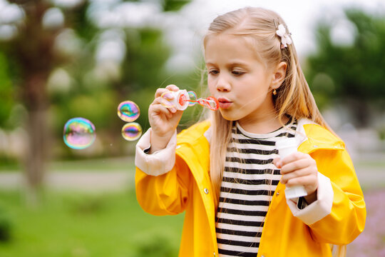 Cute little  girl in the autumn on a walk blowing soap bubbles. Childhood,  active rest, lifestyle concept.