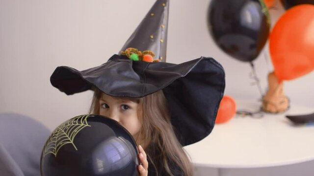 Adorable girl Inflating Balloons For Halloween