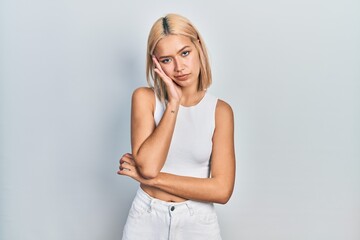 Beautiful blonde woman wearing casual style with sleeveless shirt thinking looking tired and bored with depression problems with crossed arms.