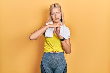 Beautiful blonde sports woman wearing workout outfit doing time out gesture with hands, frustrated...