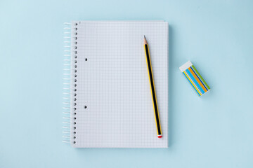 Top view of blank notepad, pencil and rubber eraser on light blue background. Study, school,...