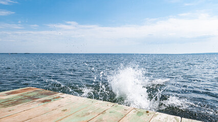 boardwalk pier, blue water and the sky in the clouds. brakes of water, the wave turns white and...