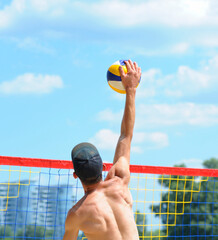 Beach volleyball. Male volley player hitting ball over the net attacking