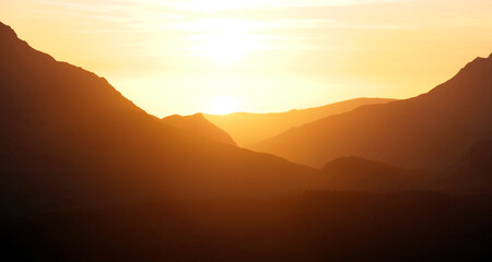 Stunning golden orange sunset in Snowdonia mountains, background.