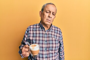 Handsome senior man with grey hair drinking a cup coffee looking sleepy and tired, exhausted for fatigue and hangover, lazy eyes in the morning.