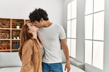 Young couple kissing and hugging standing at home.