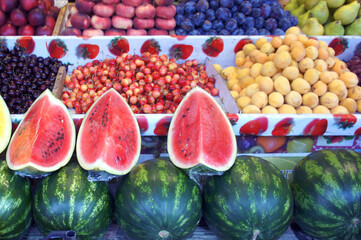Various fruits on the counter on the market. Watermelon, cherries, peaches, plums, pears.