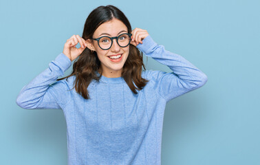 Young beautiful woman wearing casual clothes and glasses smiling pulling ears with fingers, funny...