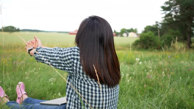 Asian woman getting up and doing stretching in a farm. Taking a deep breath and getting some fresh air. Feeling fresh and having happy face. Being in a beautiful green farm