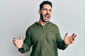 Young hispanic man wearing casual clothes crazy and mad shouting and yelling with aggressive...