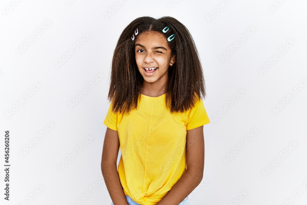 Poster young african american girl standing over white isolated background winking looking at the camera wi