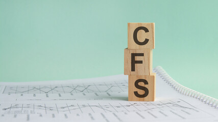 three stone cubes on the background of white financial statements, tables with the word CFS. Strong...
