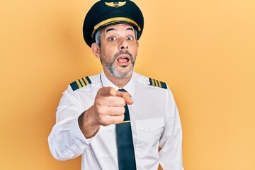 Handsome middle age man with grey hair wearing airplane pilot uniform pointing displeased and frustrated to the camera, angry and furious with you