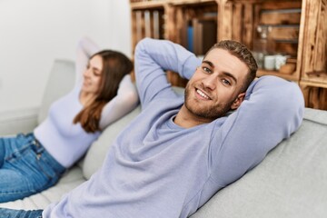 Obraz premium Young caucasian couple resting with hands on head sitting on the sofa at home.
