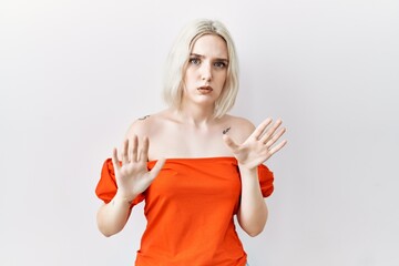 Young caucasian woman standing over isolated background moving away hands palms showing refusal and...