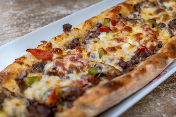 Pide, Turkish bread with meat and cheese topping, close up. Traditional Turkish cuisine on plate...
