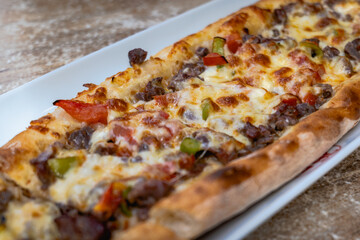 Pide, Turkish bread with meat and cheese topping, close up. Traditional Turkish cuisine on plate close-up