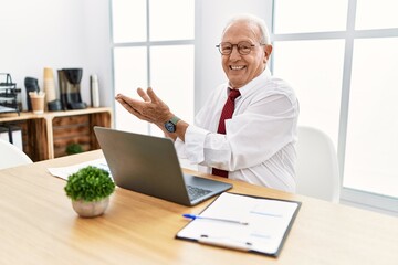 Senior man working at the office using computer laptop pointing aside with hands open palms showing copy space, presenting advertisement smiling excited happy