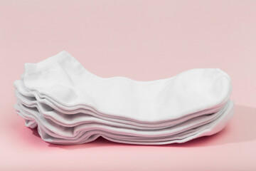 stack of white socks on pink background .