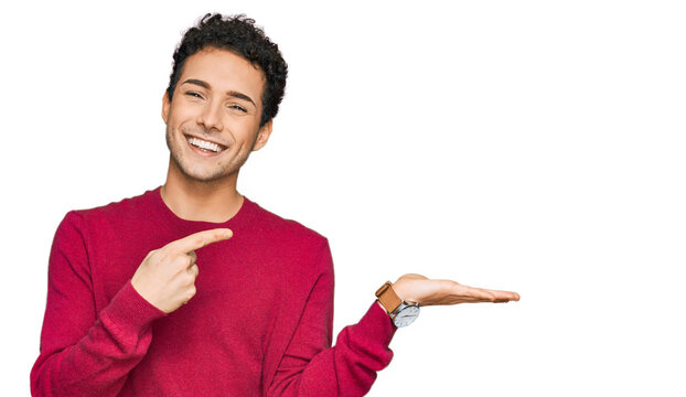 Young handsome man wearing casual clothes amazed and smiling to the camera while presenting with hand and pointing with finger.