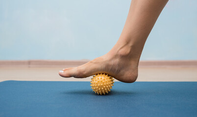 close-up of a leg rolling a yellow massage ball on a mat