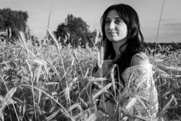 black and white photo, sunset, young, pretty, emotional brunette girl with long hair on wheat....