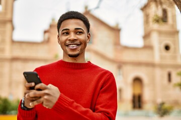 Handsome african american man outdoors using smartphone typing a message