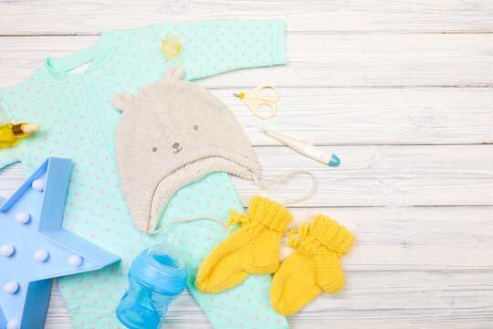 baby clothes and  attributes on a white wooden background. View from above - Image
