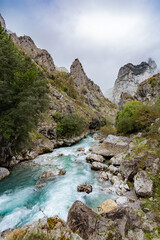 colorful autumn landscape with turquoise crystal water river between mountains and mist