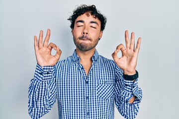 Fototapeta premium Young hispanic man wearing casual clothes relax and smiling with eyes closed doing meditation gesture with fingers. yoga concept.