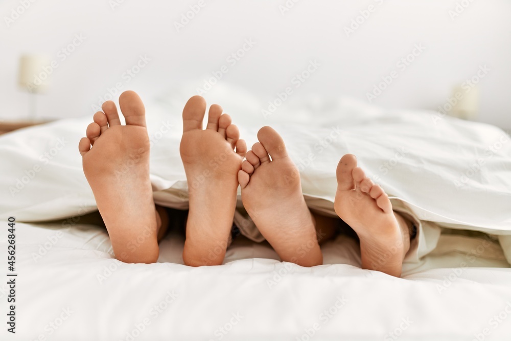 Canvas Prints Couple feet under sheets on the bed at home.