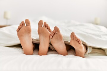 Couple feet under sheets on the bed at home.