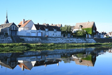 Fototapeta na wymiar Reflet des maisons de village sur la rivière au lever du soleil
