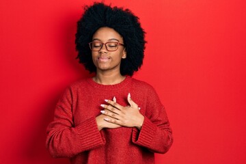 Young african american woman wearing casual clothes and glasses smiling with hands on chest, eyes...