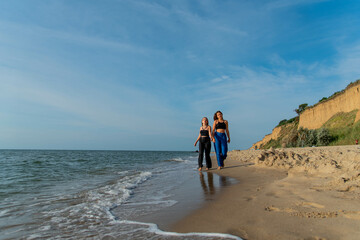 Happy young people running on beach and enjoying summer holiday. two young beautiful girls walking on beach