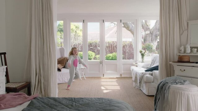 happy little girl dancing in bedroom having fun enjoying weekend morning at home doing funny dance wearing pajamas